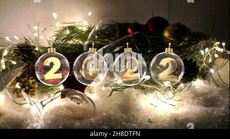 bonne année 2022 chiffres en boules de verre transparent sur la décoration avec fairylights verres à champagne dans la neige illuminée Banque D'Images
