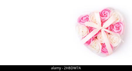 Boîte en forme de coeur pleine de fleurs de savon de rose isolées sur blanc.Le concept de soins de la peau, beauté, carte de vœux de Saint-Valentin ou bannière.Vue de dessus.FLA Banque D'Images