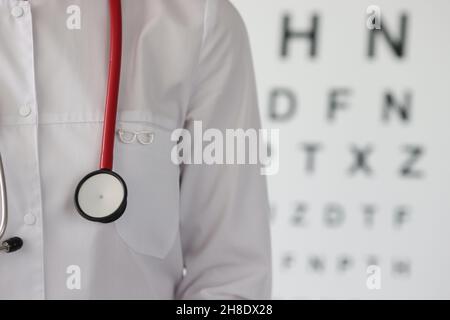 Médecin ophtalmologiste avec icône de lunettes debout sur le fond de la table de mesure de la vision de près Banque D'Images