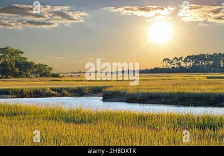 Le soleil de la fin de l'après-midi diffuse une lumière chaude sur un marais salé de Caroline du Sud à marée basse. Banque D'Images