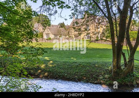 Le Manor House à côté de la rivière Windrun naissante qui coule à travers le village de Cotswold de Naunton, Gloucestershire Royaume-Uni Banque D'Images