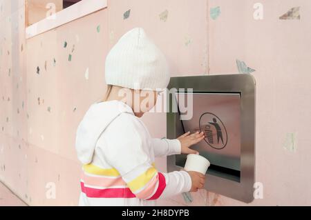 Un enfant jette un gobelet en carton en papier dans une boîte de recyclage de tri.Photo éducative de la conscience.Tri et recyclage.Séparation des déchets Banque D'Images