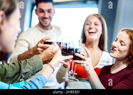 De jeunes amis multiculturels boivent et toaster du vin rouge à la fête à la maison - des gens heureux s'amuser ensemble au restaurant bar de la cave de vinification Banque D'Images