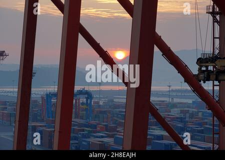 Coucher de soleil observé par la construction de grues portiques actionnées par des stevedores. Banque D'Images