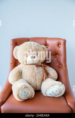 Vieux triste face ours en peluche assis seul sur un fauteuil dans la salle de séjour.Décrit la solitude et la dépression. Banque D'Images