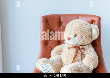 Vieux triste face ours en peluche assis seul sur un fauteuil dans la salle de séjour.Décrit la solitude et la dépression. Banque D'Images