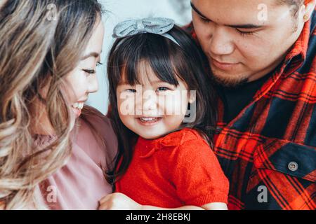 Père de famille asiatique, mère avec fille petite fille célébrant Noël ou nouvel an.Race mixte maman, papa, fille décorant Christa arbre huggi Banque D'Images