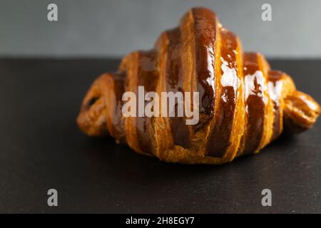 Un croissant français fraîchement préparé avec une garniture au chocolat se trouve sur le plateau en ardoise.De délicieuses pâtisseries.Copier l'espace.Mise au point sélective. Banque D'Images