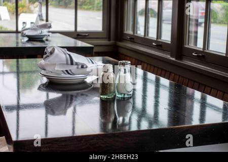 Vue inclinée sur une table en bois à l'intérieur d'un restaurant, recouvert de serviettes propres et d'argenterie Banque D'Images