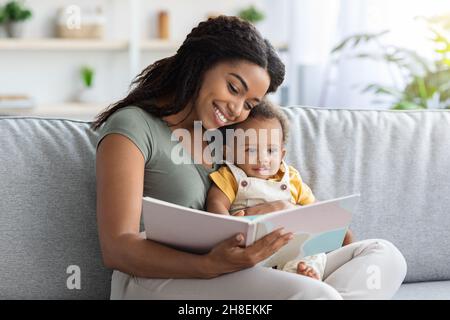 Concept de développement précoce.Livre de lecture de maman noire affectueuse à son enfant tout-petit Banque D'Images