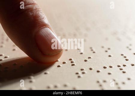 Un doigt après la lecture d'une page écrite en braille, le système de lecture tactile en relief pour les aveugles Banque D'Images