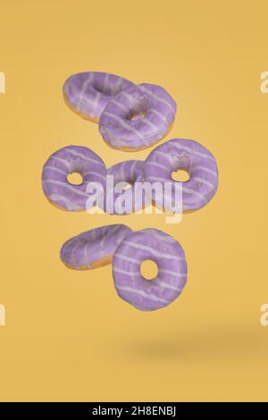 Beignets à la décoration violette avec des bleuets en mouvement tombant ou volant sur fond jaune.Dessert minimal et concept sucré Banque D'Images