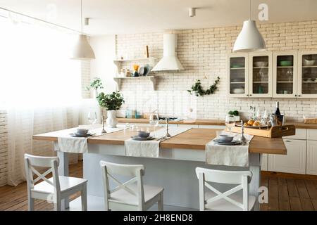 Cuisine scandinave confortable ou salle à manger intérieur avec table et chaises en bois, mobilier de cuisine clair et ustensiles Banque D'Images
