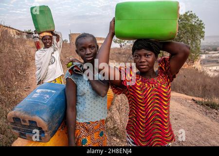 Des filles africaines transportant de l'eau douce dans un village à l'extérieur de Bamako, au Mali. Banque D'Images