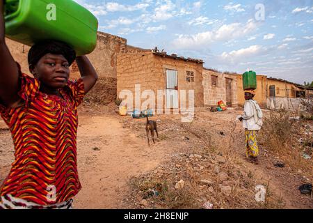 Des filles africaines transportant de l'eau douce dans un village à l'extérieur de Bamako, au Mali. Banque D'Images