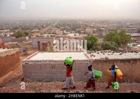 Des filles africaines transportant de l'eau douce dans un village à l'extérieur de Bamako, au Mali. Banque D'Images