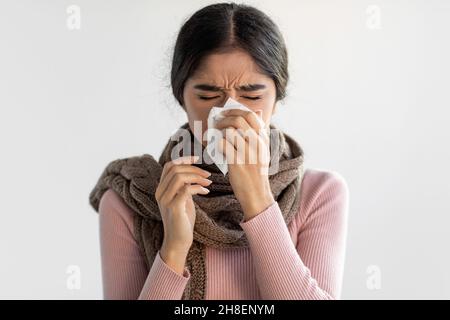 Portrait de triste bouleversé jeune femme indienne en foulard souffle son nez et essuie le nez avec des tissus Banque D'Images