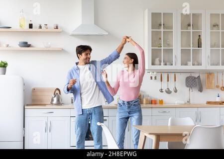 Souriant beau couple européen millénaire s'amuser ensemble, se sentir heureux, danser dans la cuisine Banque D'Images