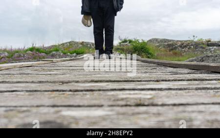 Ockero, Suède - 10 juin 2021 : un homme marchant sur le petit pont en bois avec sa casquette dans la main Banque D'Images