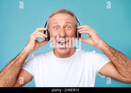 Portrait de tête d'un homme mature excité portant un casque sans fil Banque D'Images