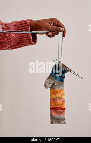 Image d'arrière-plan minimale de la main de femme tenant des chaussettes en tricot confortables par fil, espace de copie Banque D'Images
