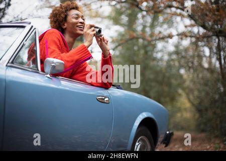 Jeune femme heureuse avec un appareil photo numérique convertible dans le parc Banque D'Images