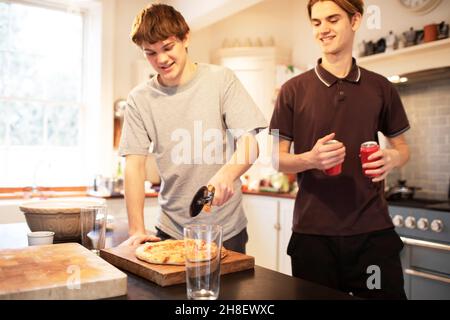 Les adolescents trancheuses de pizza dans la cuisine Banque D'Images