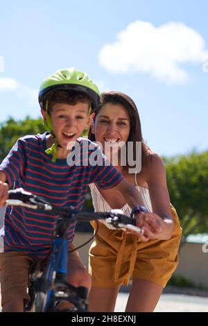 Bonne mère aidant son à faire du vélo Banque D'Images