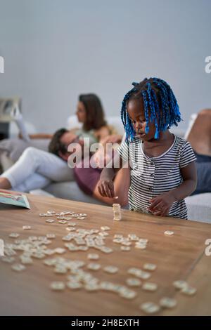 Adorable petite fille empilable carreaux scrabble sur une table basse Banque D'Images