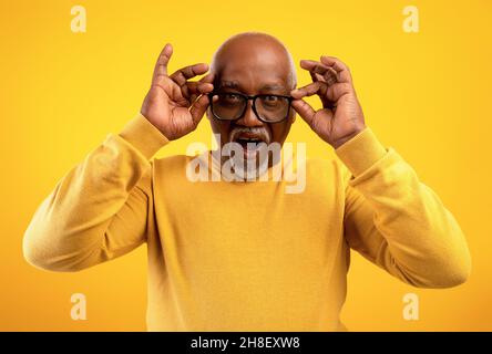 Portrait de l'homme afro-américain senior dans les lunettes ouvrant la bouche dans l'excitation, ne peut pas croire énorme vente ou remise Banque D'Images