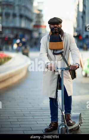 Portrait beau homme élégant sur scooter électrique poussée en ville Banque D'Images