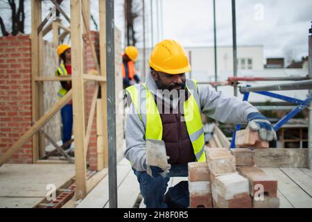 Ouvrier de la construction mâle posant des briques sur le chantier de construction Banque D'Images