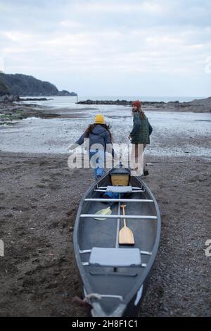 Jeune couple tirant en canoë sur la plage Banque D'Images