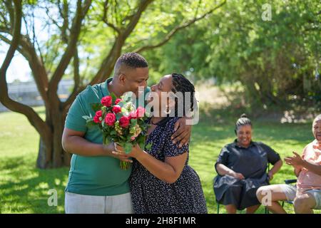 Couple heureux avec bouquet de roses dans le parc d'été Banque D'Images