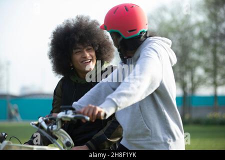 Des amis adolescents heureux à vélo dans le parc Banque D'Images