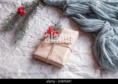 Boîte cadeau à côté de la nappe vintage gris et feuilles d'épinette avec baies rouges sur fond noir, composition festive sur fond clair Banque D'Images