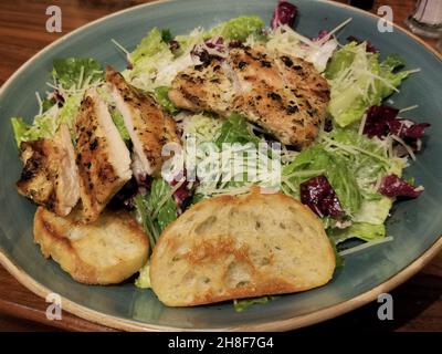 Salade César au poulet grillé servie sur une assiette en céramique verte Banque D'Images