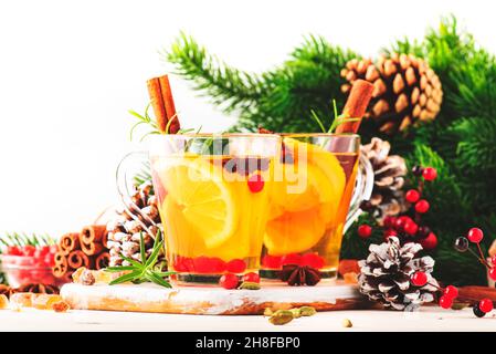 Thé chaud d'hiver avec citron, canneberges, herbes et épices dans le cadre de table de Noël ou du nouvel an, fond blanc, espace de copie Banque D'Images