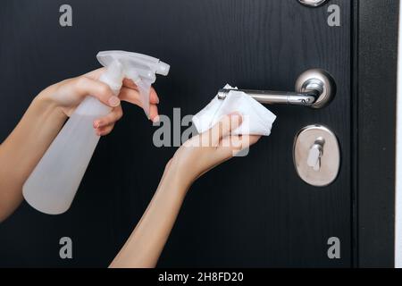 Nettoyage des poignées de porte noires avec une lingette humide antiseptique.Femme main utilisant une serviette pour nettoyer la liaison de la porte de la chambre à la maison.Désinfectez la prévention des surfaces dans Banque D'Images