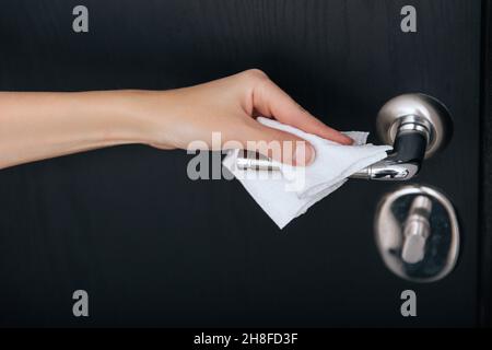 Nettoyage des poignées de porte noires avec une lingette humide antiseptique.Femme main utilisant une serviette pour nettoyer la liaison de la porte de la chambre à la maison.Désinfectez la prévention des surfaces dans Banque D'Images