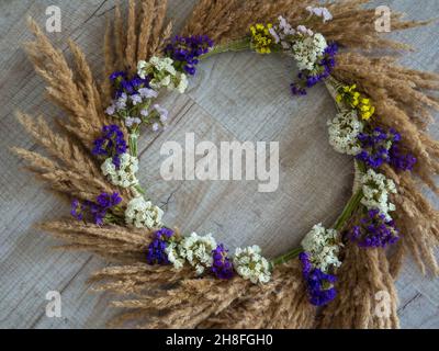 Couronne d'automne créative avec pampas d'herbe et de fleurs sauvages sur fond de bois Banque D'Images