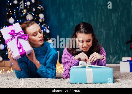 Deux belles amies ouvrent des cadeaux à l'arbre de Noël de la nouvelle année Banque D'Images