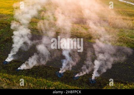 Vue aérienne des feux de déchets agricoles provenant de l'herbe sèche et de la paille brûlée avec de la fumée épaisse polluant l'air pendant la saison sèche sur les terres agricoles Banque D'Images