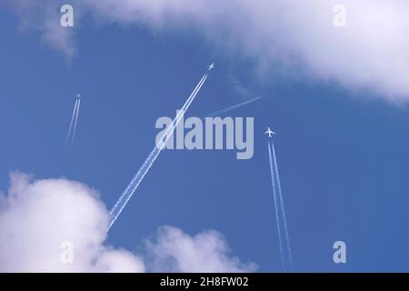 De nombreux avions à réaction de passagers à distance volent en haute altitude sur un ciel bleu clair laissant derrière eux une trace blanche de fumée de contrail.Centre de transport aérien très fréquenté Banque D'Images