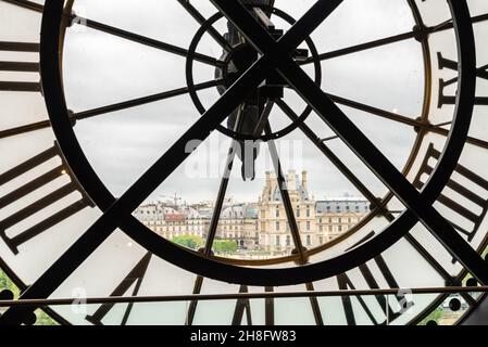 Vue sur le Louvre à travers une grande horloge du Musée d'Orsay à Paris, France Banque D'Images