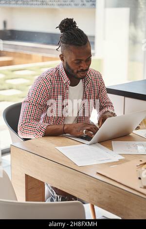 Jeune homme concentré travaillant sur son ordinateur portable Banque D'Images