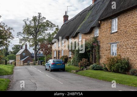 Scène de rue avec des bâtiments en pierre de chaume dans le joli village d'Ashby St Ledgers, Northamptonshire, Royaume-Uni Banque D'Images