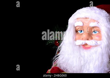 Motif de Noël photo d'un gros plan du visage d'une poupée du Père Noël. La photo est prise sur fond noir et en format horizontal. Banque D'Images