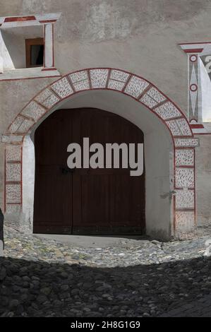 La décoration sgraffito peinte en rouge, blanc et gris renforce la large entrée ronde et les fenêtres profondes d'une maison familiale traditionnelle Engadiner dans le village alpin historique d'Ardez, dans le canton des Grisons ou des Grisons, dans l'est de la Suisse. Banque D'Images