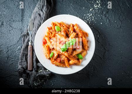 Bolognaise de pène chaude au parmesan et au basilic.Cuisine italienne.Pâtes fraîches avec sauce. Banque D'Images